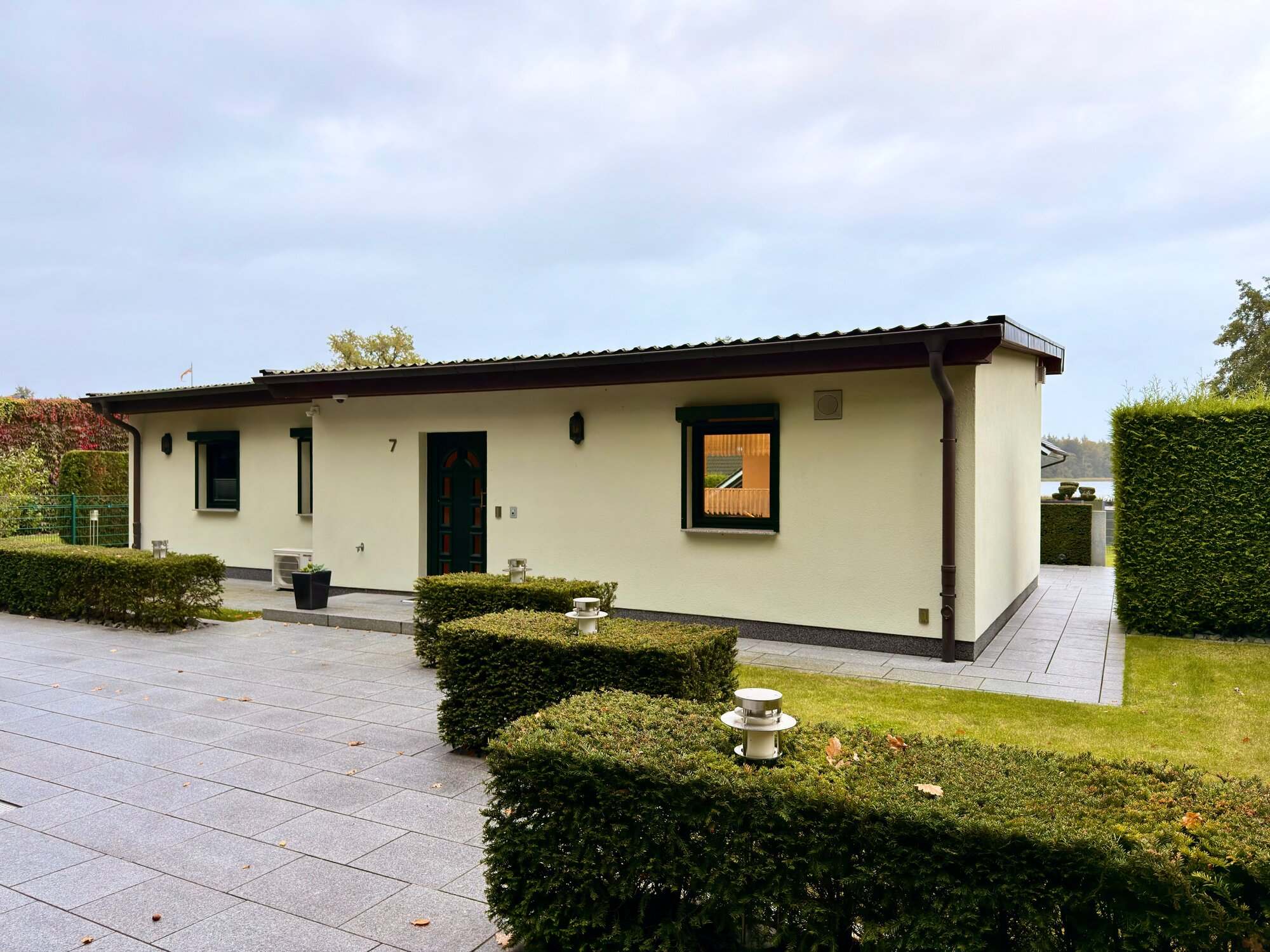 Hausfront mit Eingang Nr. 7, Hecken-Säulen und Steinplatten-Pfad