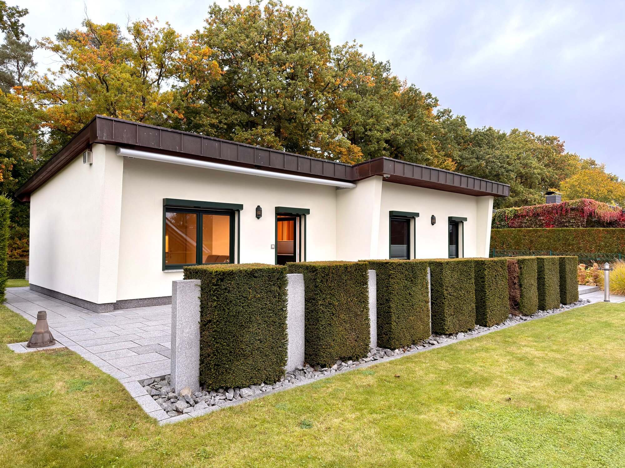 Haus von der Gartenseite mit Hortensien-Säulen-Reihe und Herbstlaub