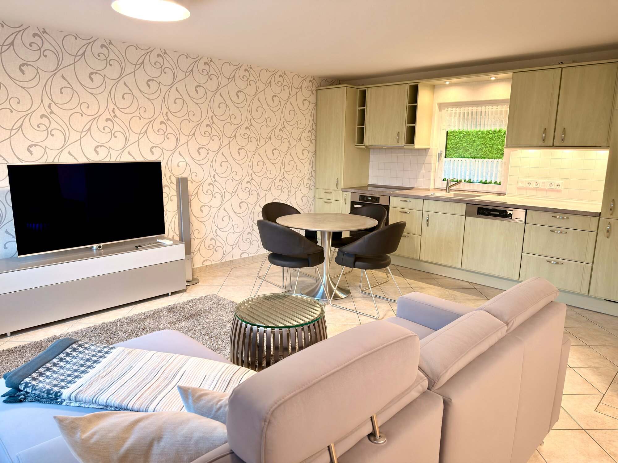 Wohnbereich mit Sofa, Smart-TV und offener Küche