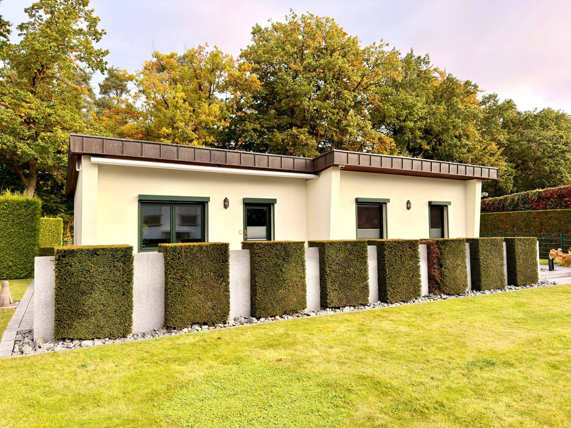 Rückansicht des Ferienhauses Kobe mit Hecke und Granit-Säulen