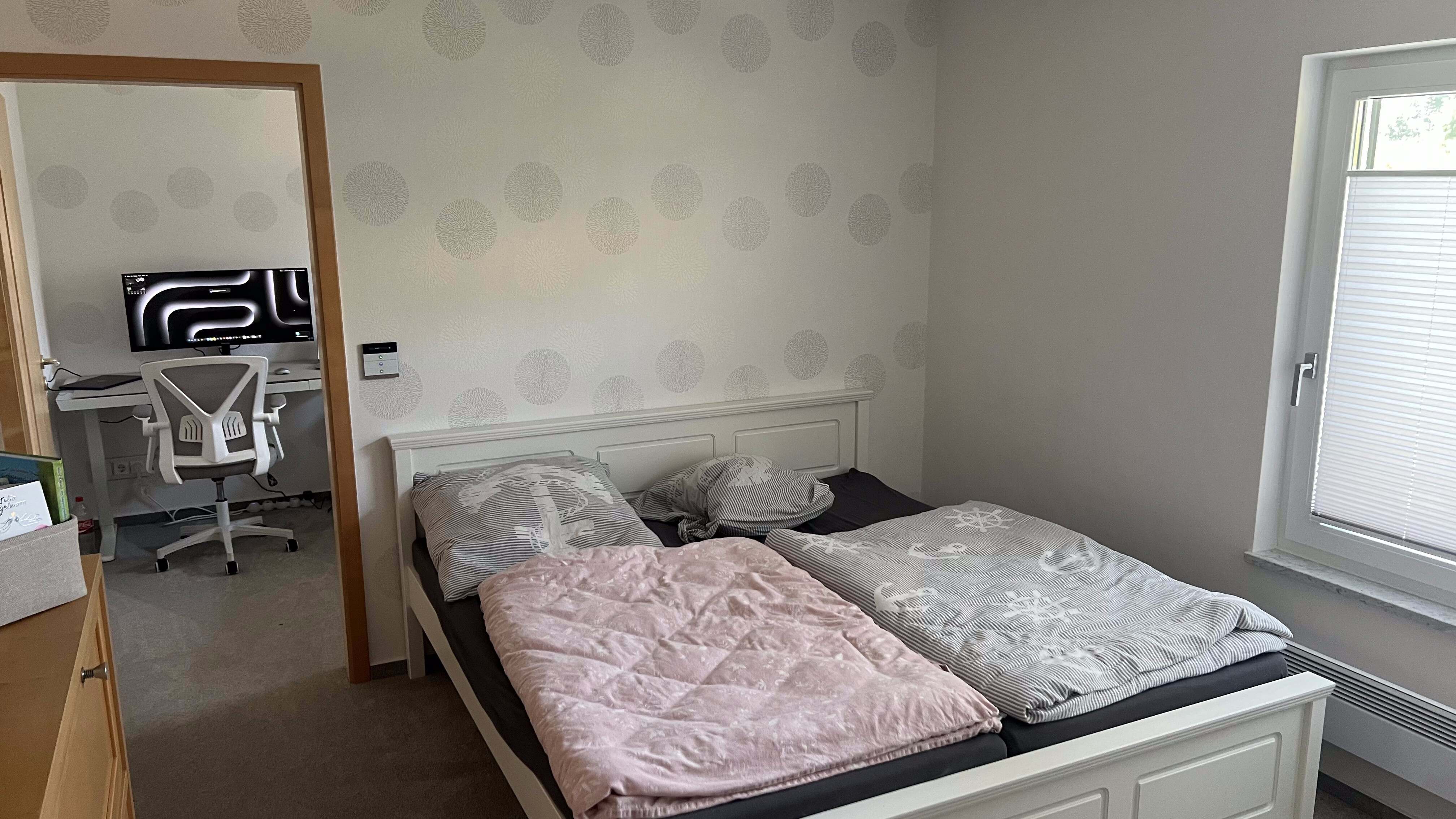 Schlafzimmer mit Doppelbett und offener Tür zum Arbeitsraum