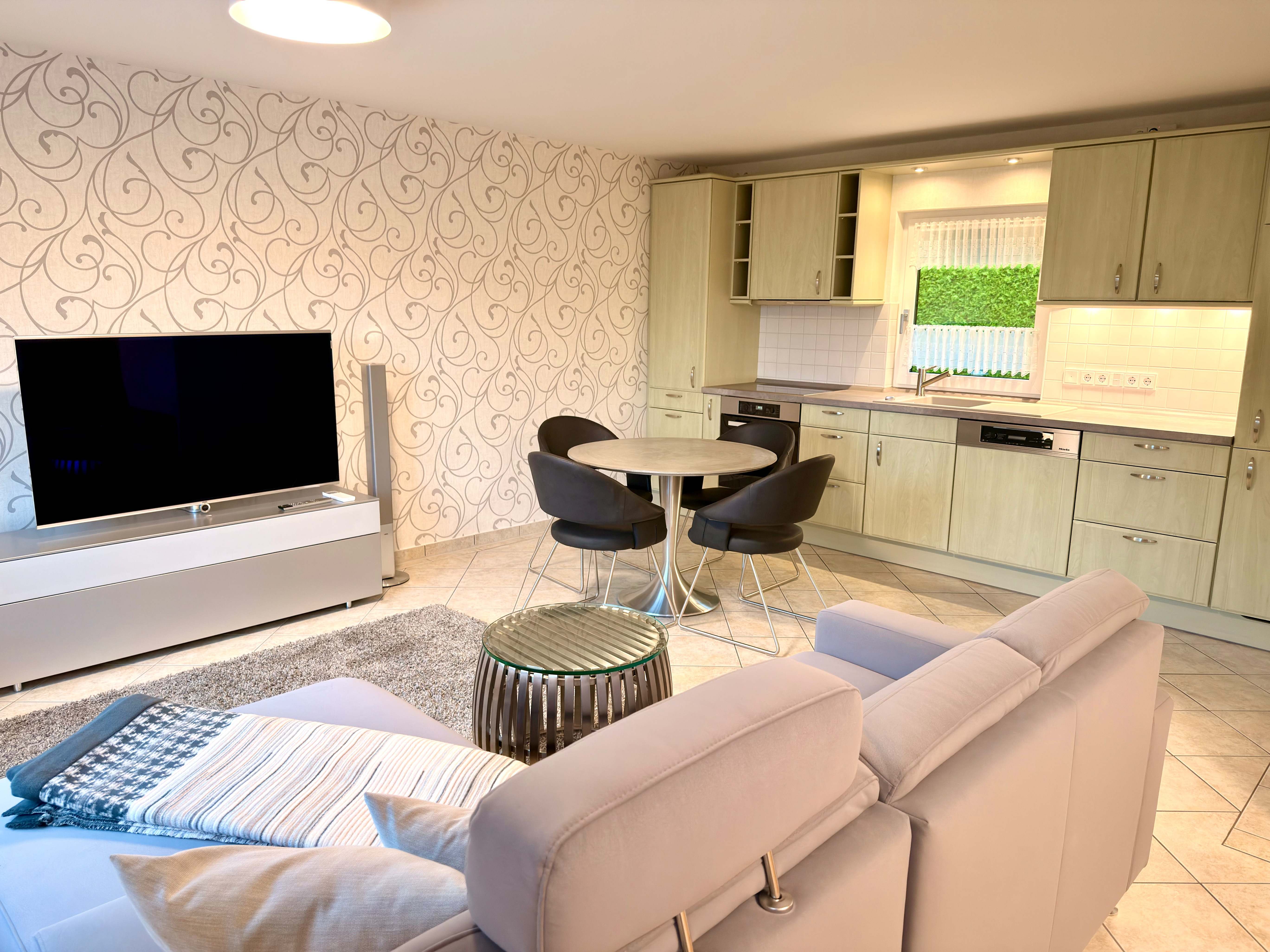 Wohnbereich des Ferienhauses Kobe mit Sofa, Smart-TV und offener Küche